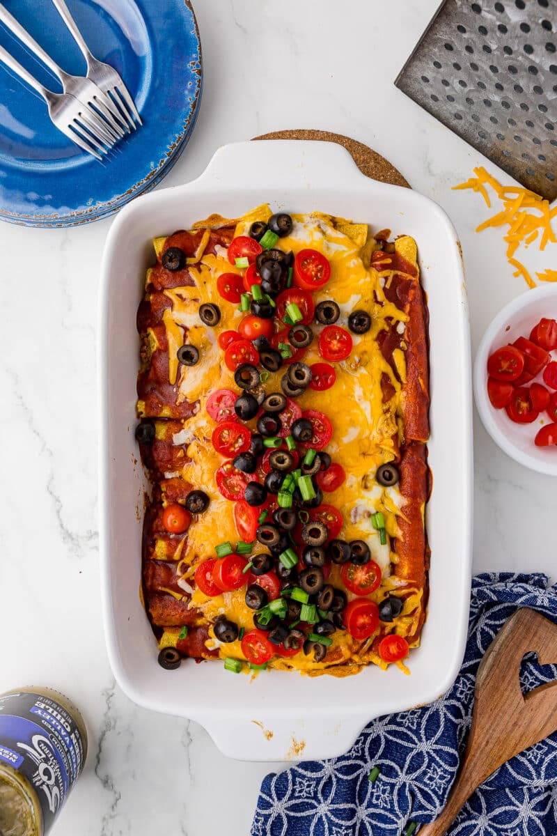 green onions, sliced olives, sliced tomatoes, on the taquitos casserole on a white countertop
