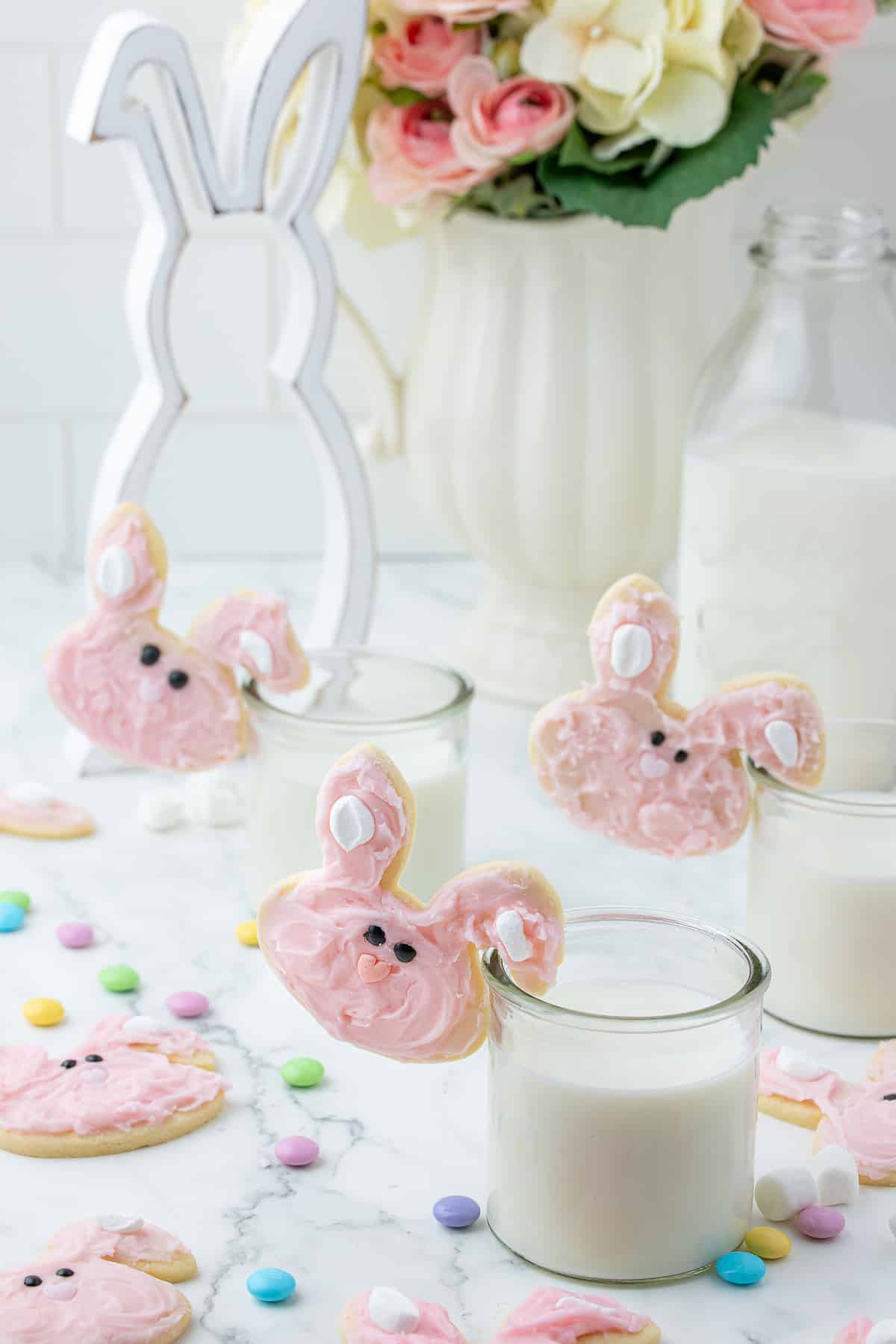 Easter bunny sugar cookies with ears hooked on to glasses of milk