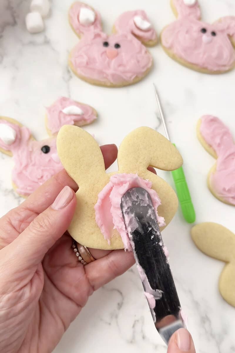 Applying pink frosting to Easter sugar cookies