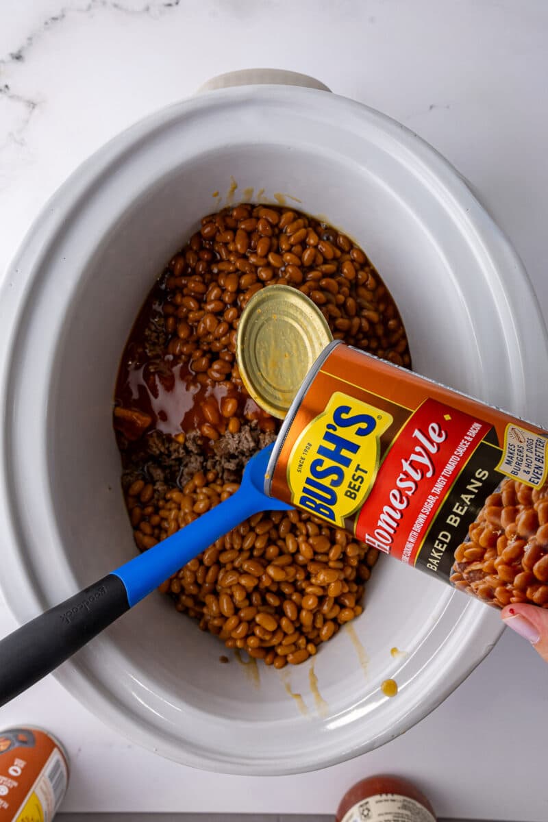 adding bush's best baked beans into a crock pot