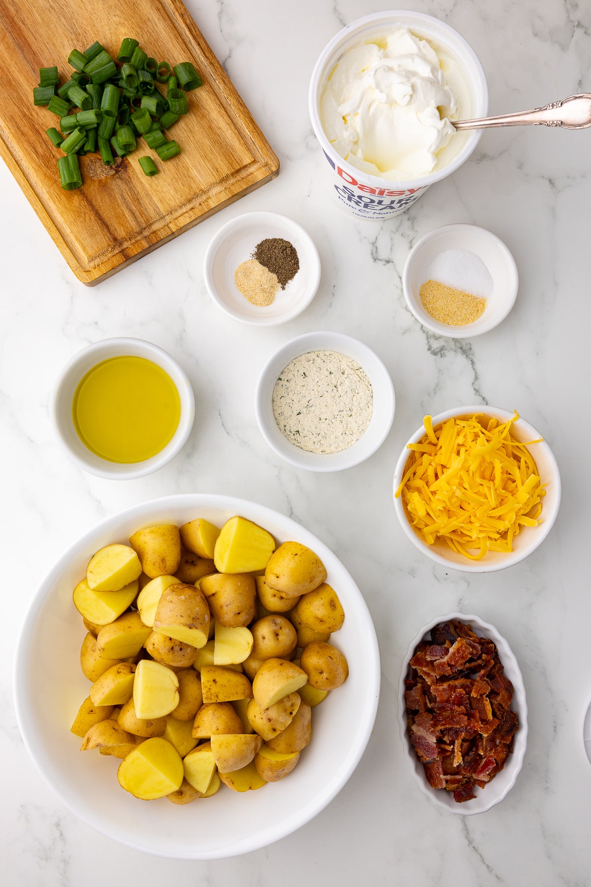 Ingredients for homemade ranch potatoes including toppings like cheese, sour cream and spices