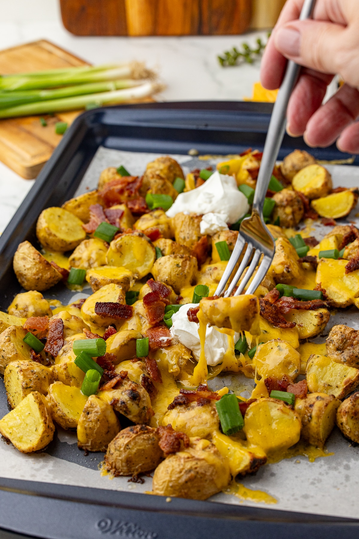 Baking sheet with potato wedges covered with cheese and toppings