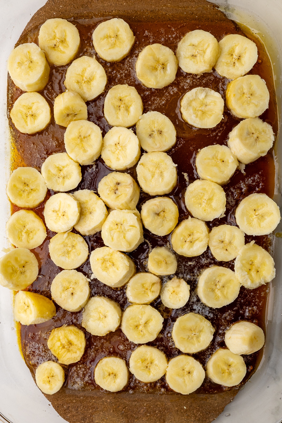 sliced bananas on caramelized sugar in the bottom of a 9x13 deep dish casserole