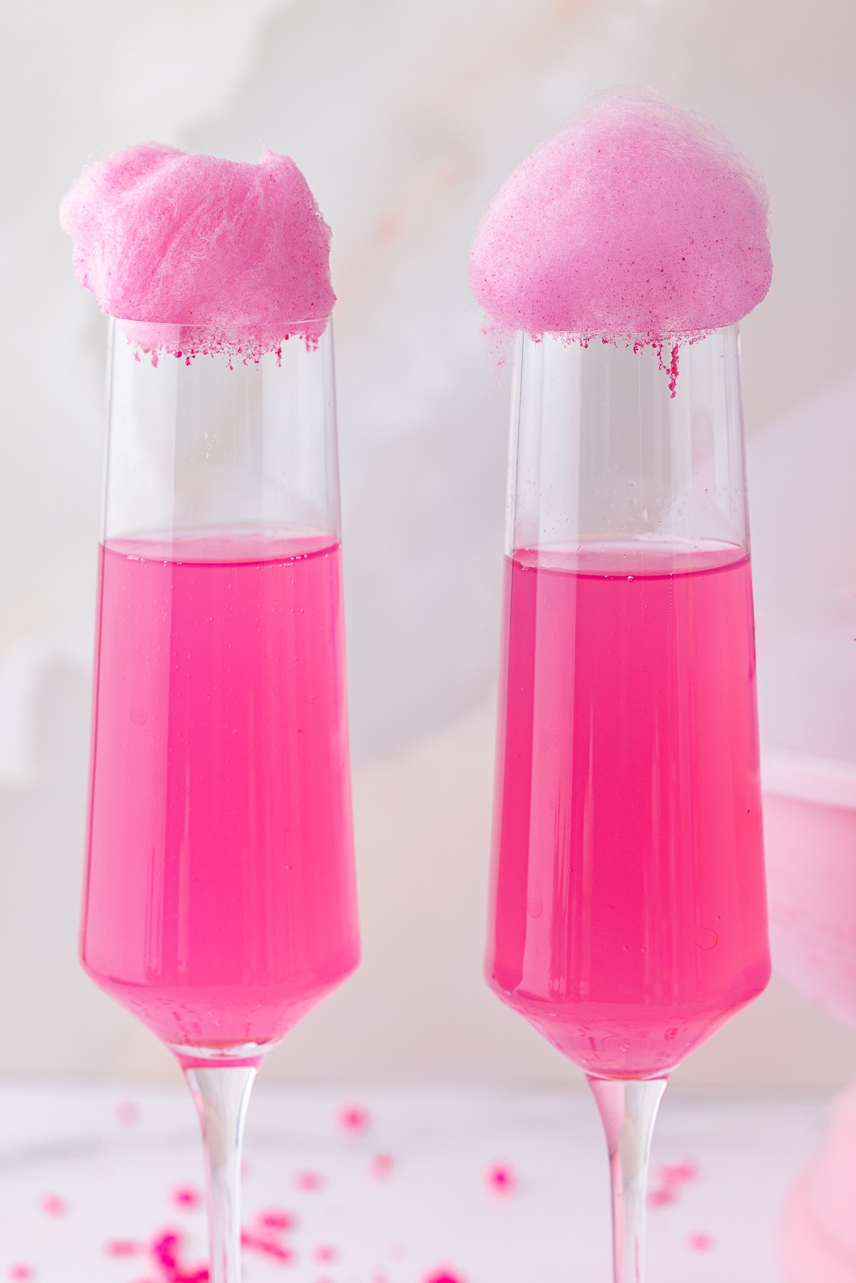 closeup of pink cotton candy over a pink champagne flute