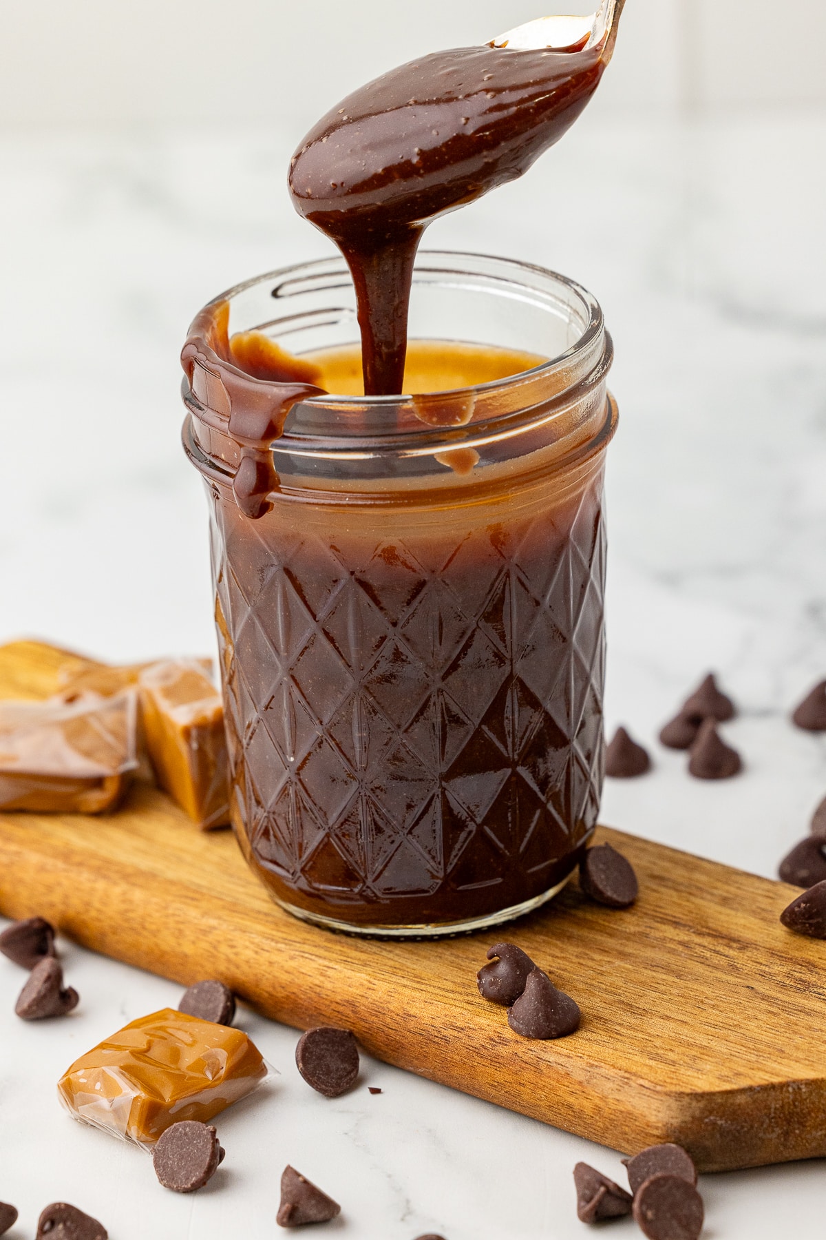 chocolate sauce in a canning jar with a spoonful drizzling in