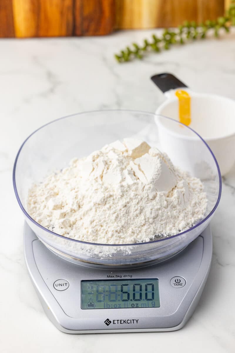 one cup of flour in a kitchen scale with an oxo dry measuring cups in the background