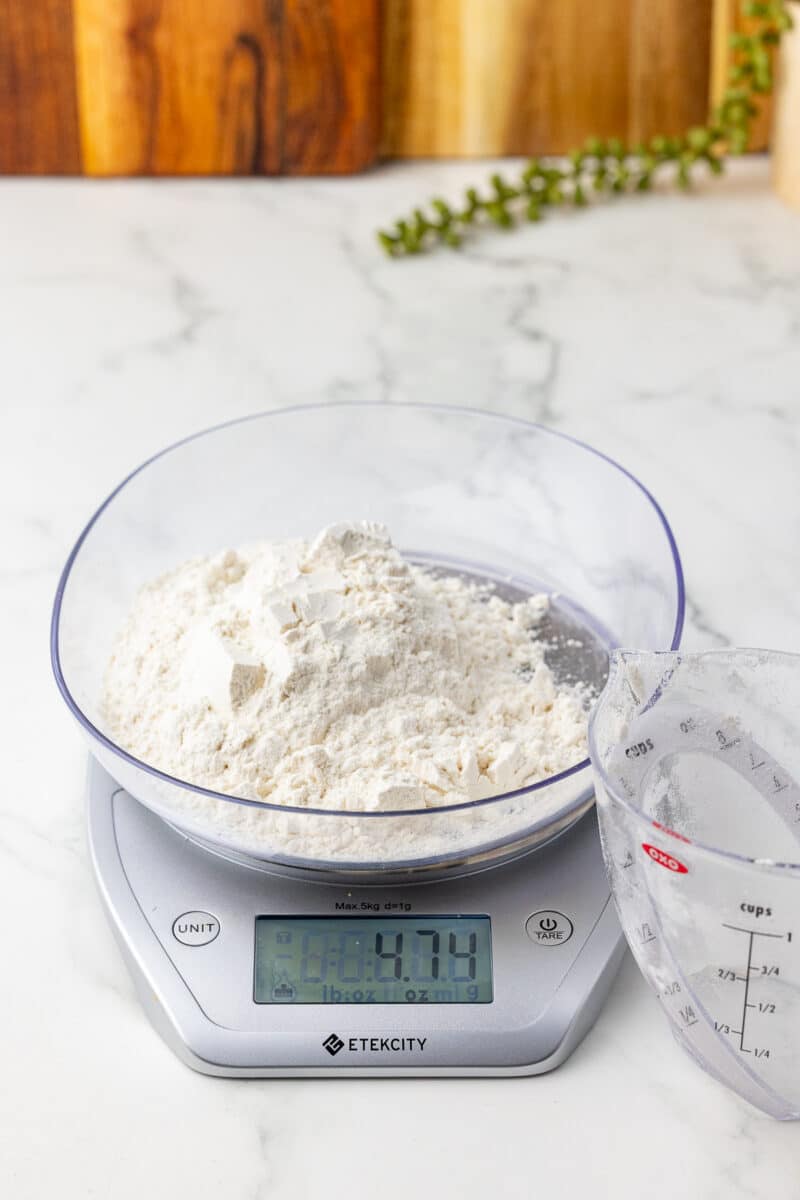 one cup of flour on a kitchen scale with an oxo liquid measuring cup in the foreground