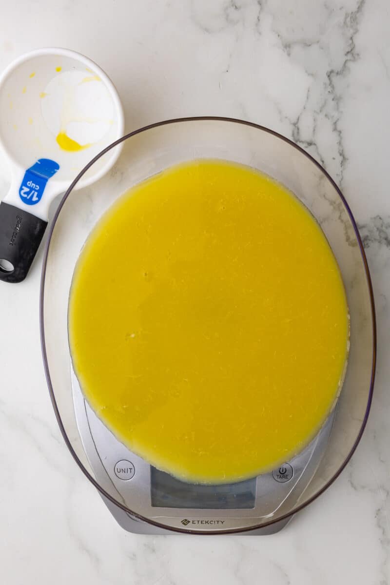 orange juice being measured on a scale with a dry measuring cup in the background on a white countertop