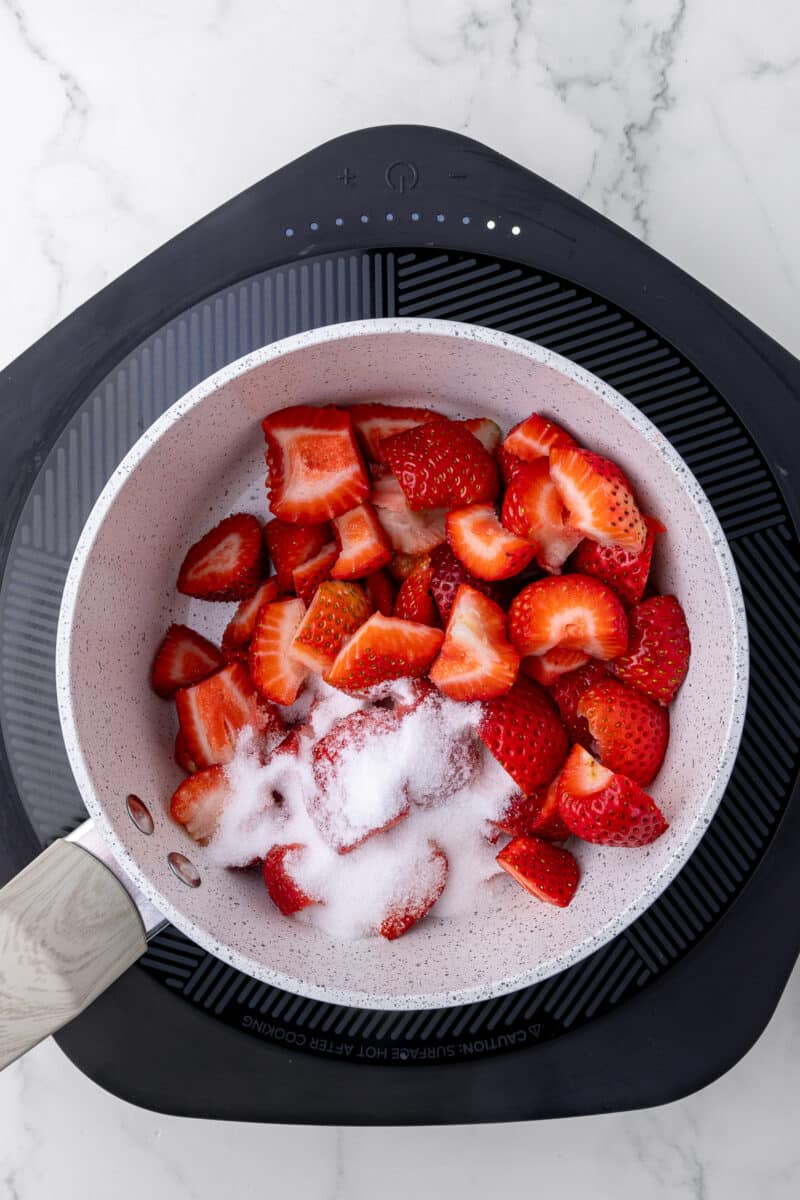 saucepan with strawberries and sugar on a hotplate