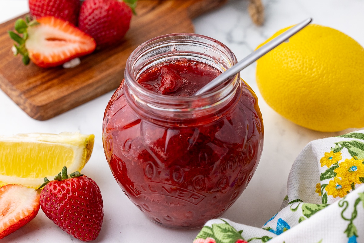strawberry compote in a Kilner strawberry shaped jar with lemons and strawberries in the background