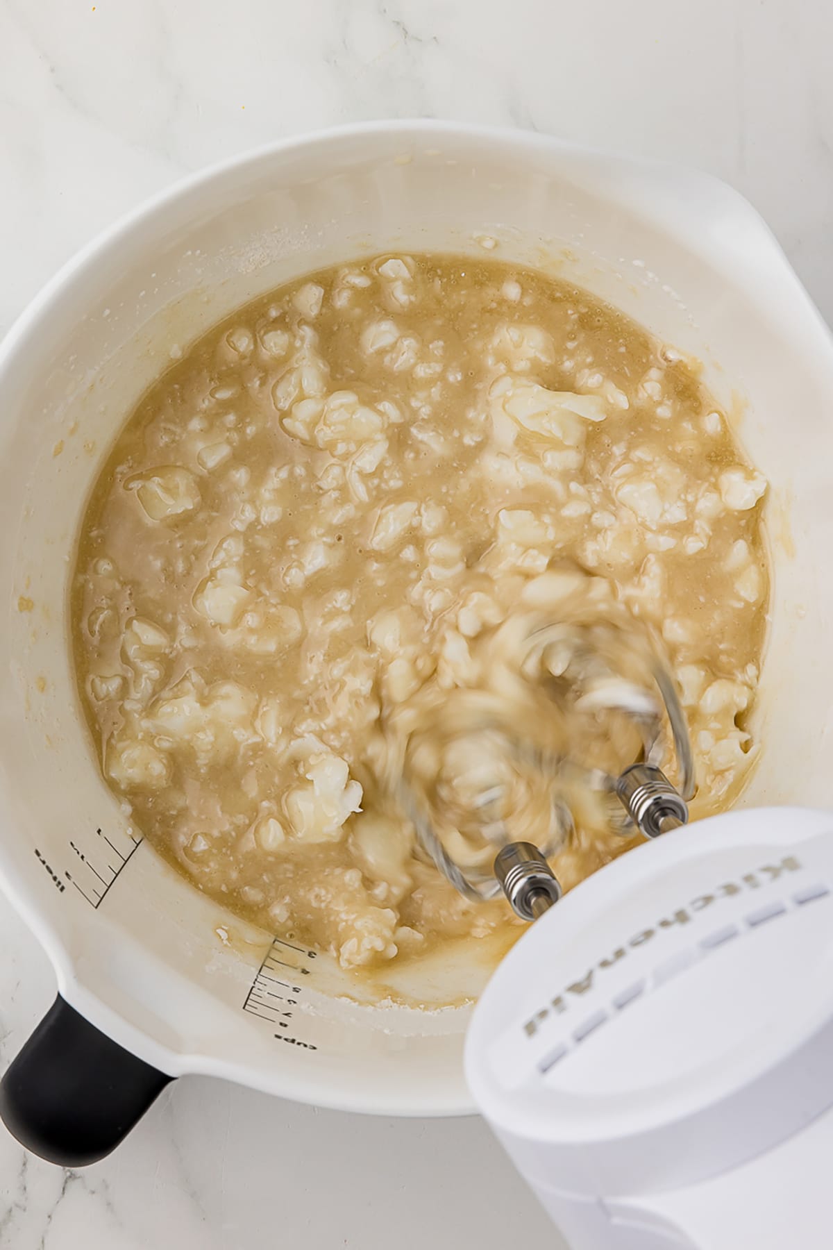oil, shortening, and flour in a white batter bowl with kitchenaid hand mixer