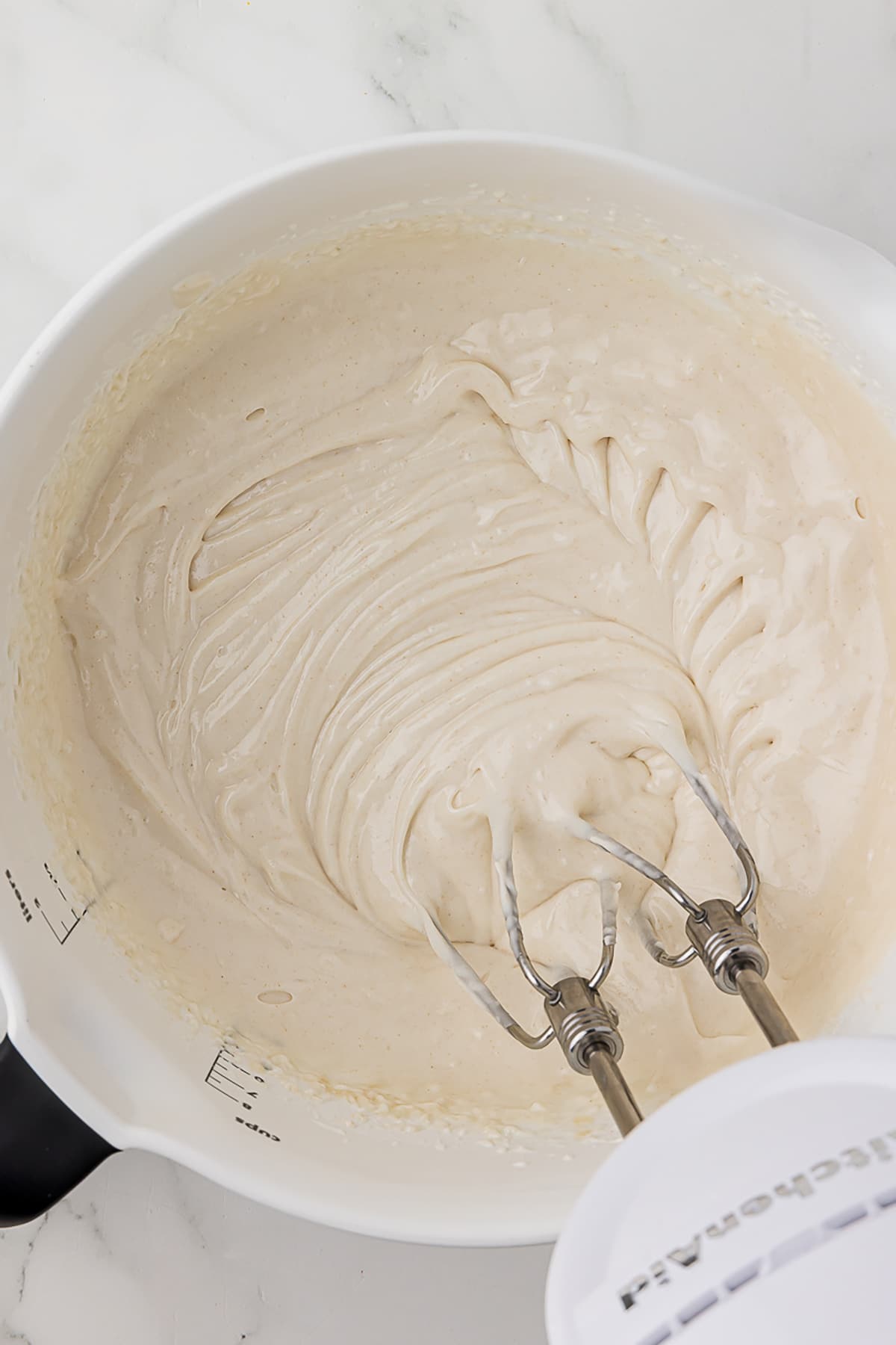 kitchenaid mixer in white batter bowl mixing cake goop