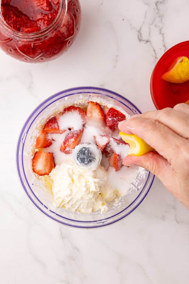 cream cheese, strawberries, sugar and vanilla in a cuisinart hand held food processor with a lemon being squeezed
