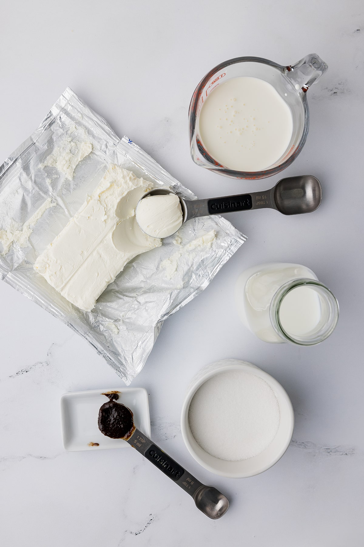 Ingredients for making homemade vanilla ice cream including cream cheese, sugar and vanilla