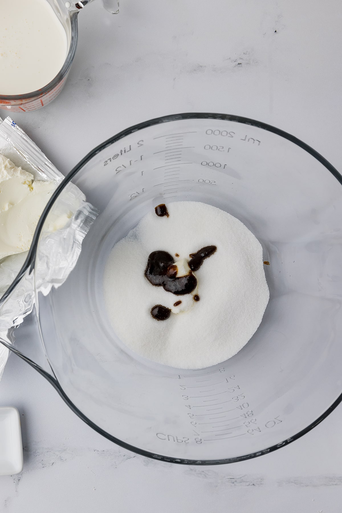 Clear mixing bowl with ice cream ingredients and vanilla