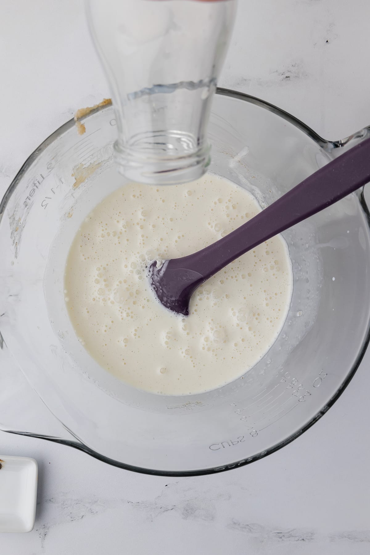 Cream, sugar and ice cream ingredients in a clear mixing bowl