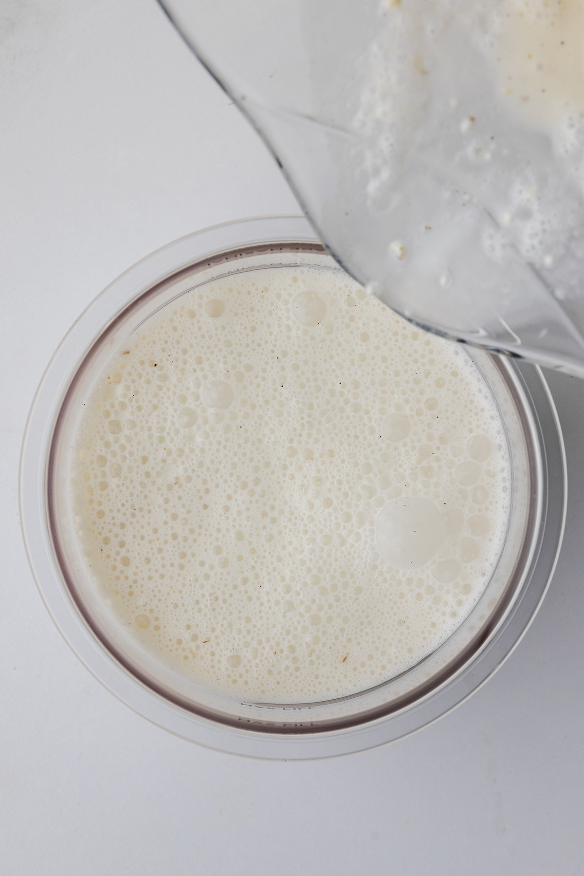 Pouring liquid homemade ice cream ingredients into a Ninja Creami pint container