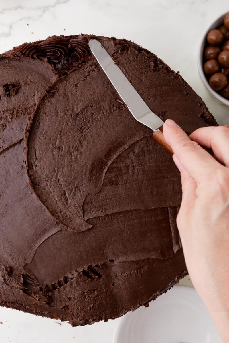 smoothing out frosting on a chocolate cake