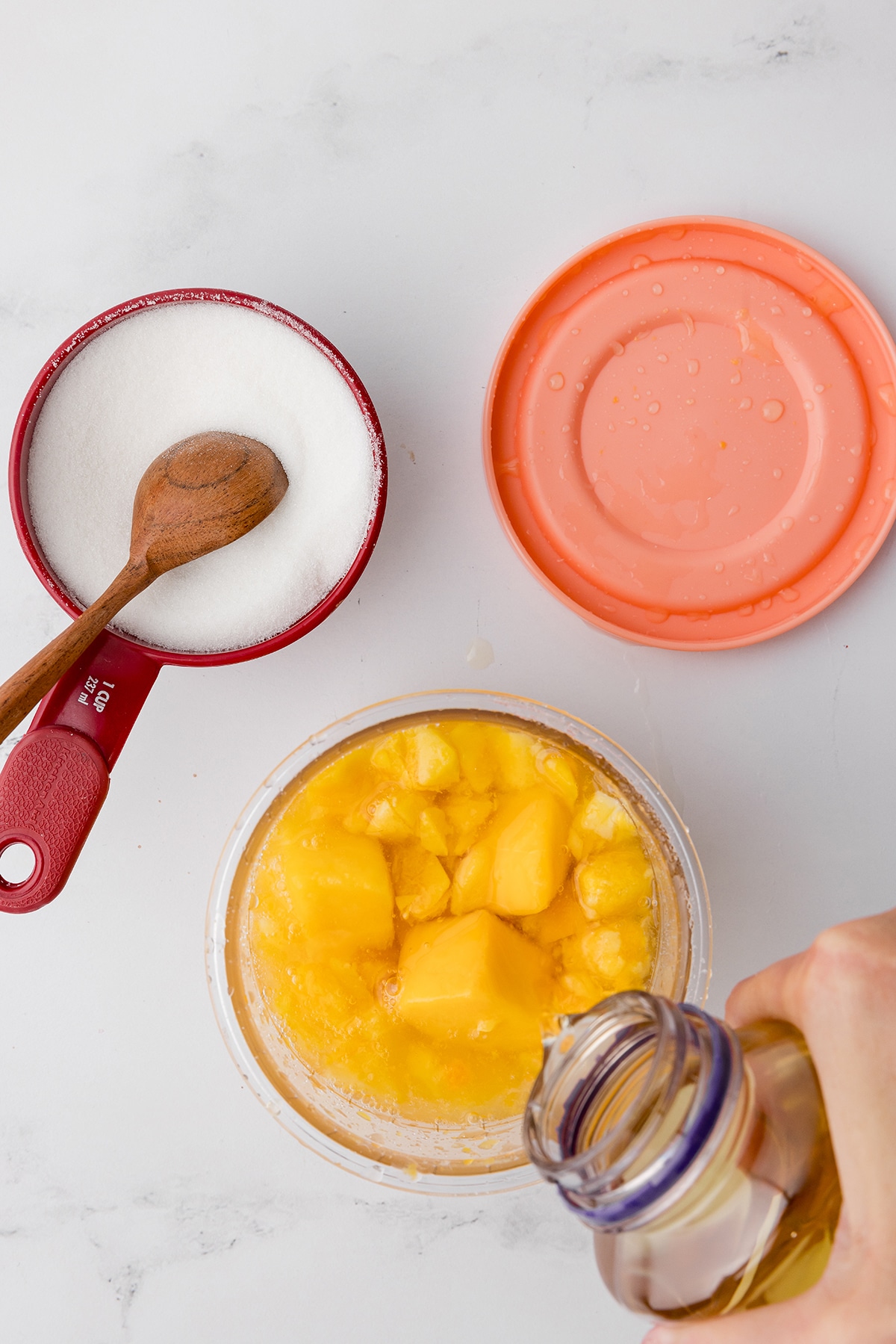 pouring white grape juice into a ninja creami pint container with mango chunks inside