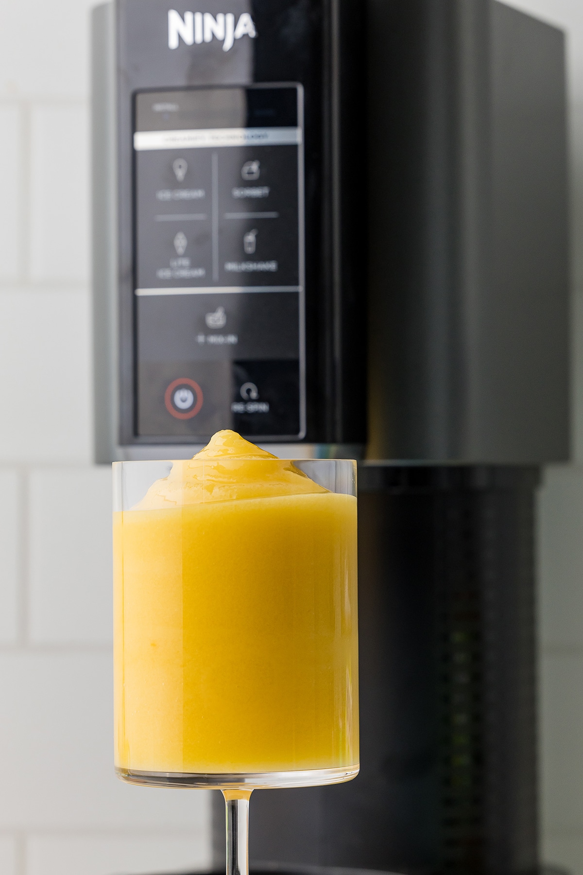 ninja creami ice cream maker behind a mango slushie