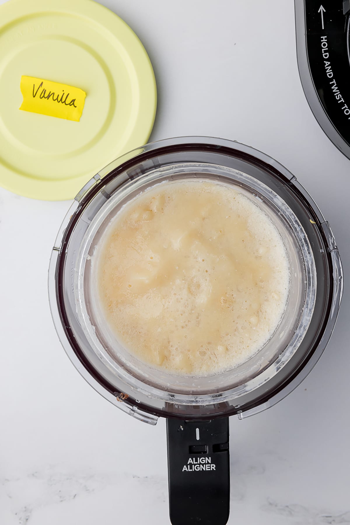 frozen vanilla protein ice cream in the ninja creami pot on a white countertop