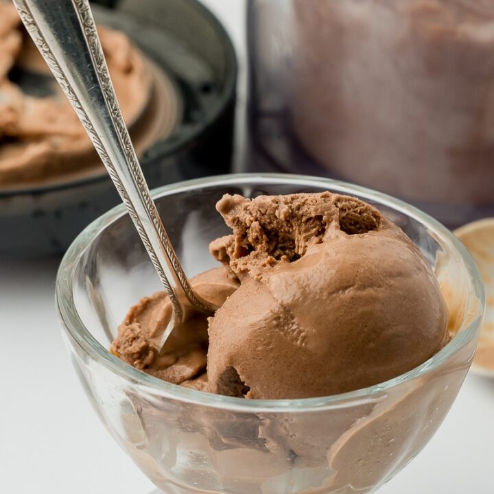 scoop of chocolate ice cream in an ice cream sundae bowl with a silver spoon