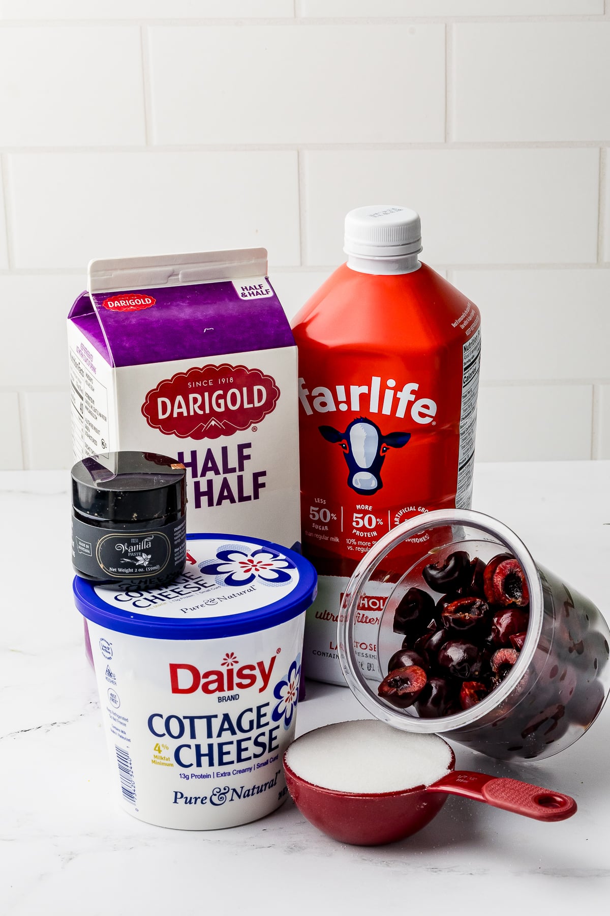 ingredients for cherry ice cream including half and half, cottage cheese, whole milk, sugar, vanilla, and pitted cherries