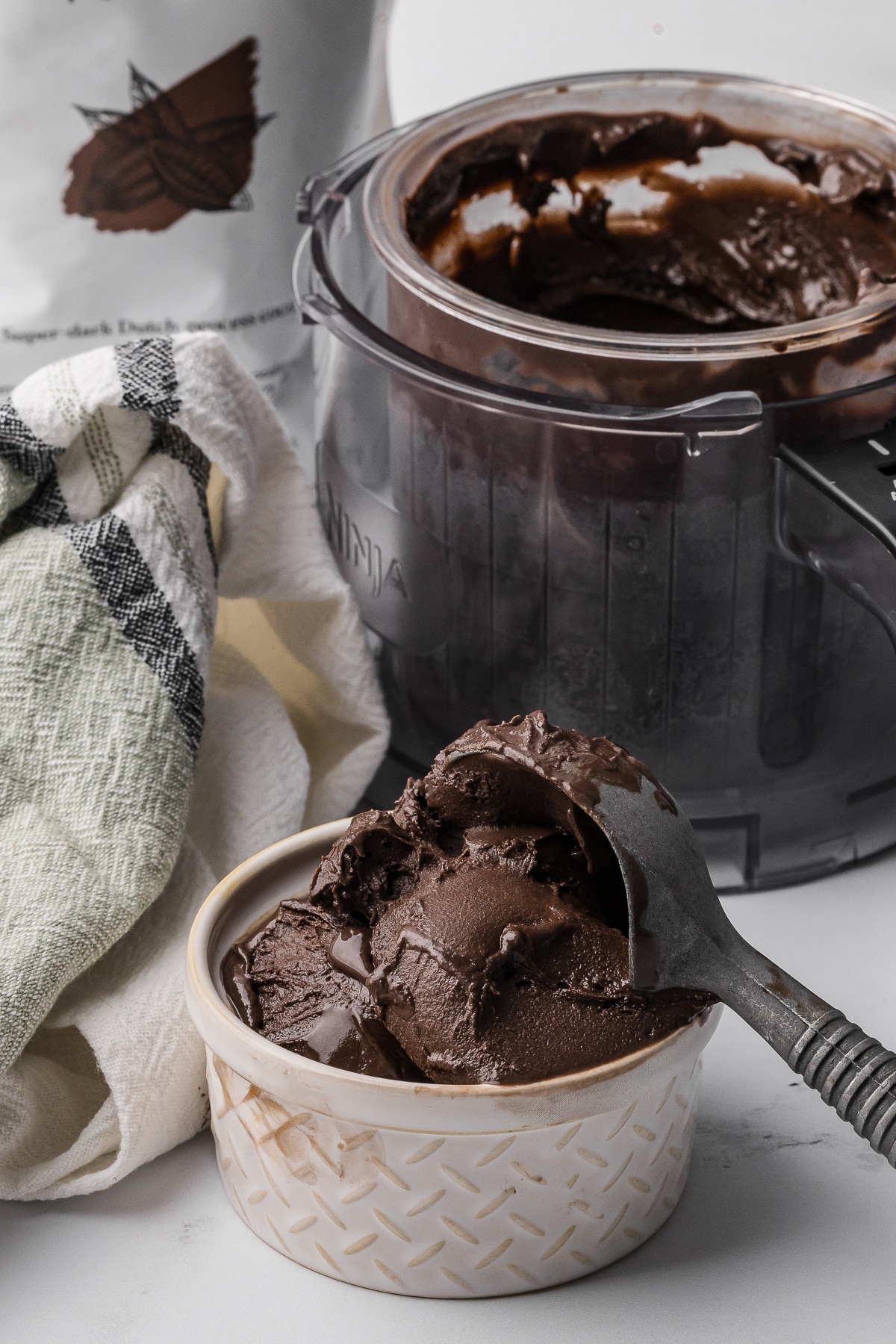 dark chocolate ice cream in a small bowl with a ninja creami pint in the background