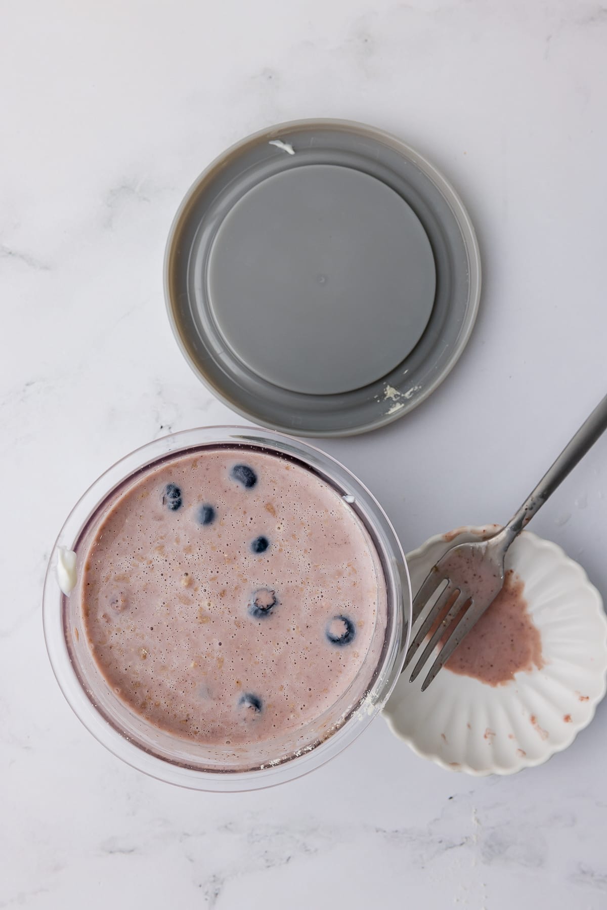 acai mixture in a ninja creami pint jar, grey lid, and a fork on a white countertop