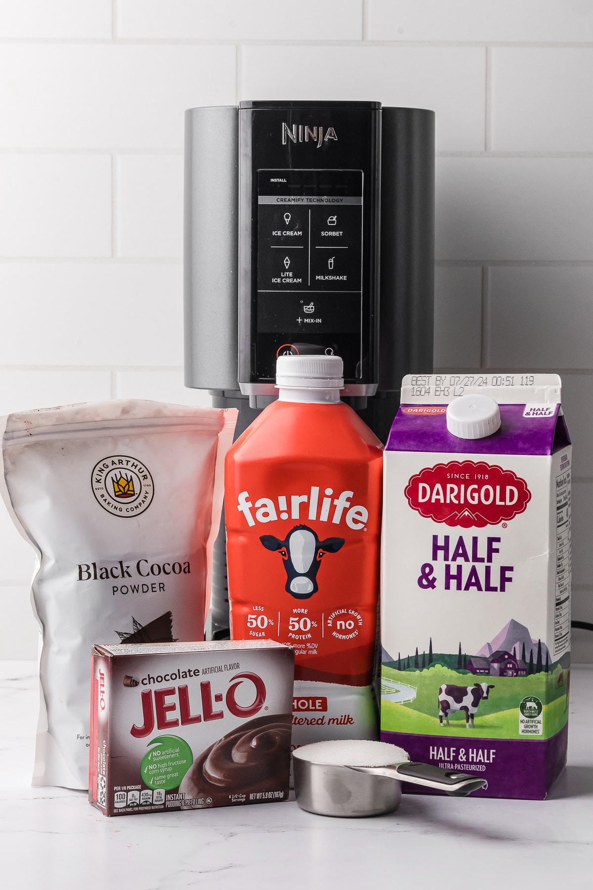 Ingredients for chocolate ice cream including black cocoa powder, fairlife whole milk, half and half, chocolate jello, and half a cup of sugar