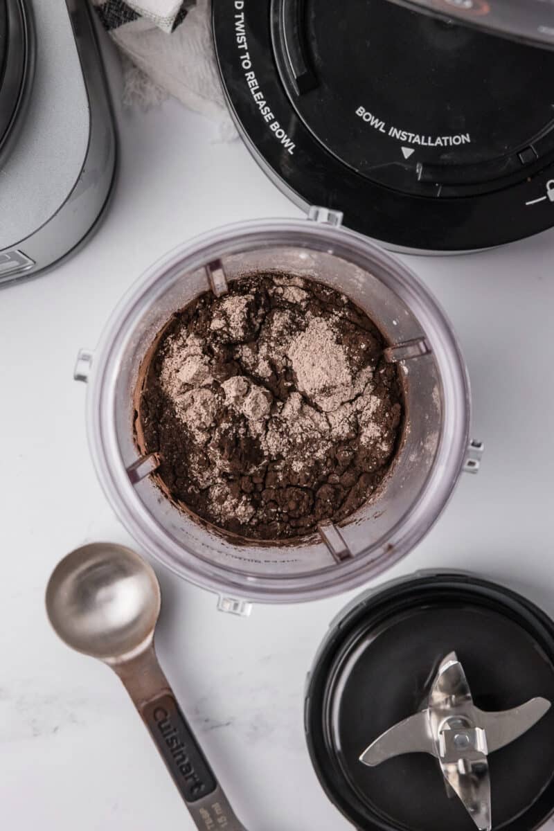 ninja creami pint jar with ingredients inside sitting on a white counter with cuisinart tablespoon