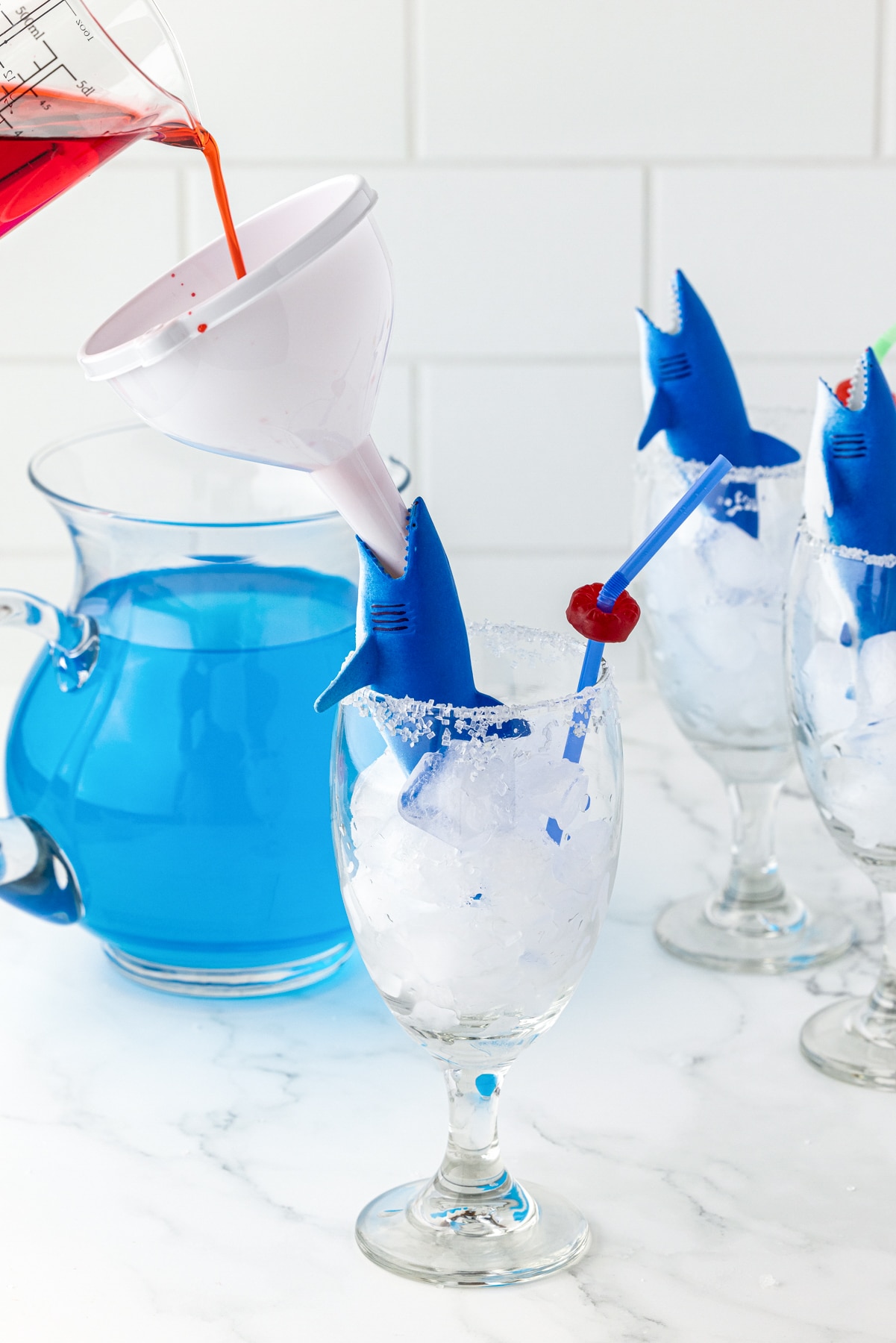 white funnel in the mouth of a shark with grenadine being poured into the mouth