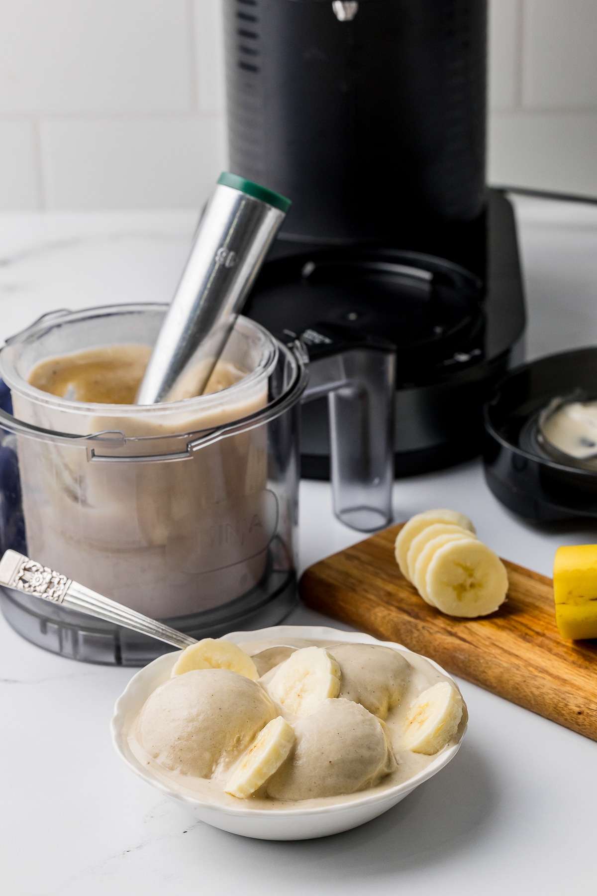 Ninja Creami ice cream machine with pint of ice cream with a bowl of icecream with banana slices