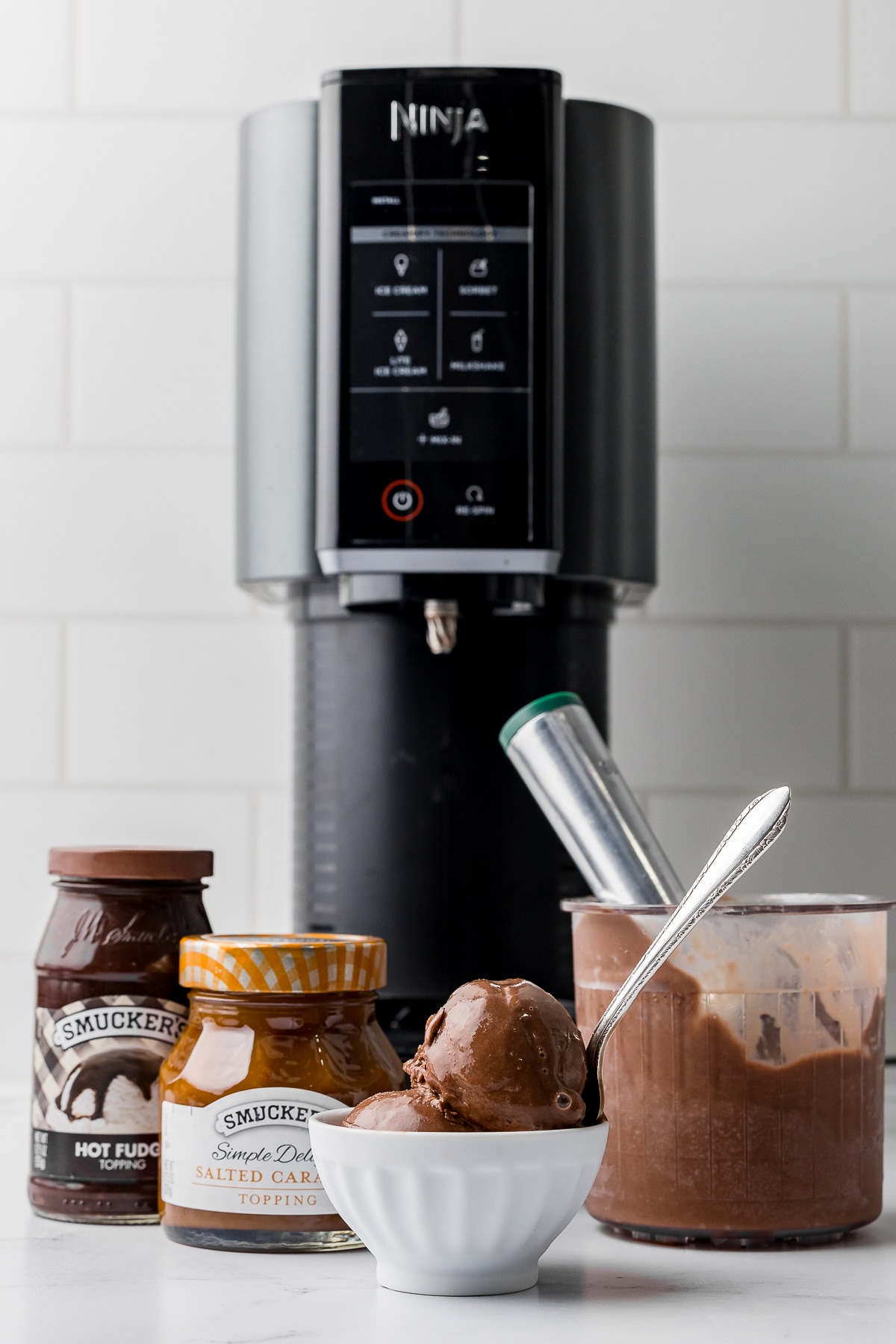 chocolate ice cream in a white bowl in front of a ninja creami ice cream maker