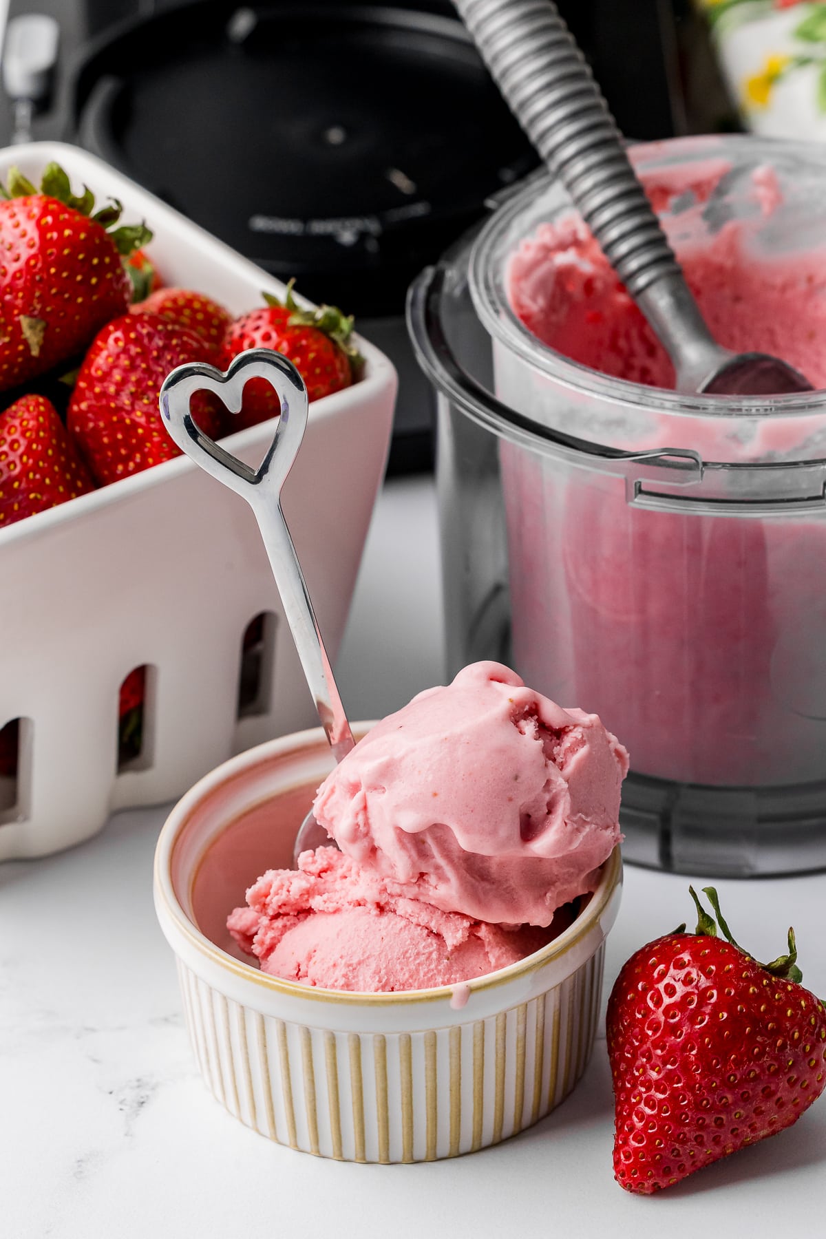 heart spoon in a ramekin filled with ninja creami strawberry ice cream with a fresh strawberry