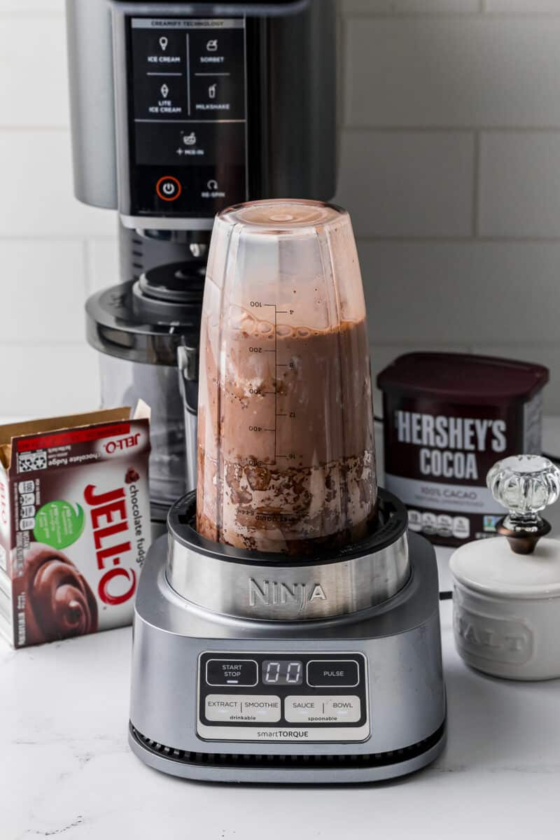 ninja smart torque mixing ninja creami ice cream mixture, chocolate fudge jello, hershey's cocoa in the back with a creami machine