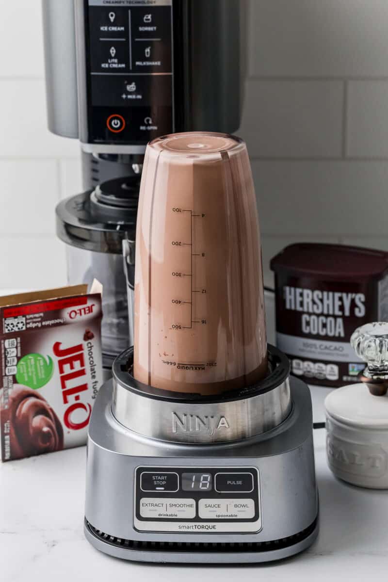 ninja smart torque mixing ninja creami ice cream mixture, chocolate fudge jello, hershey's cocoa in the back with a creami machine