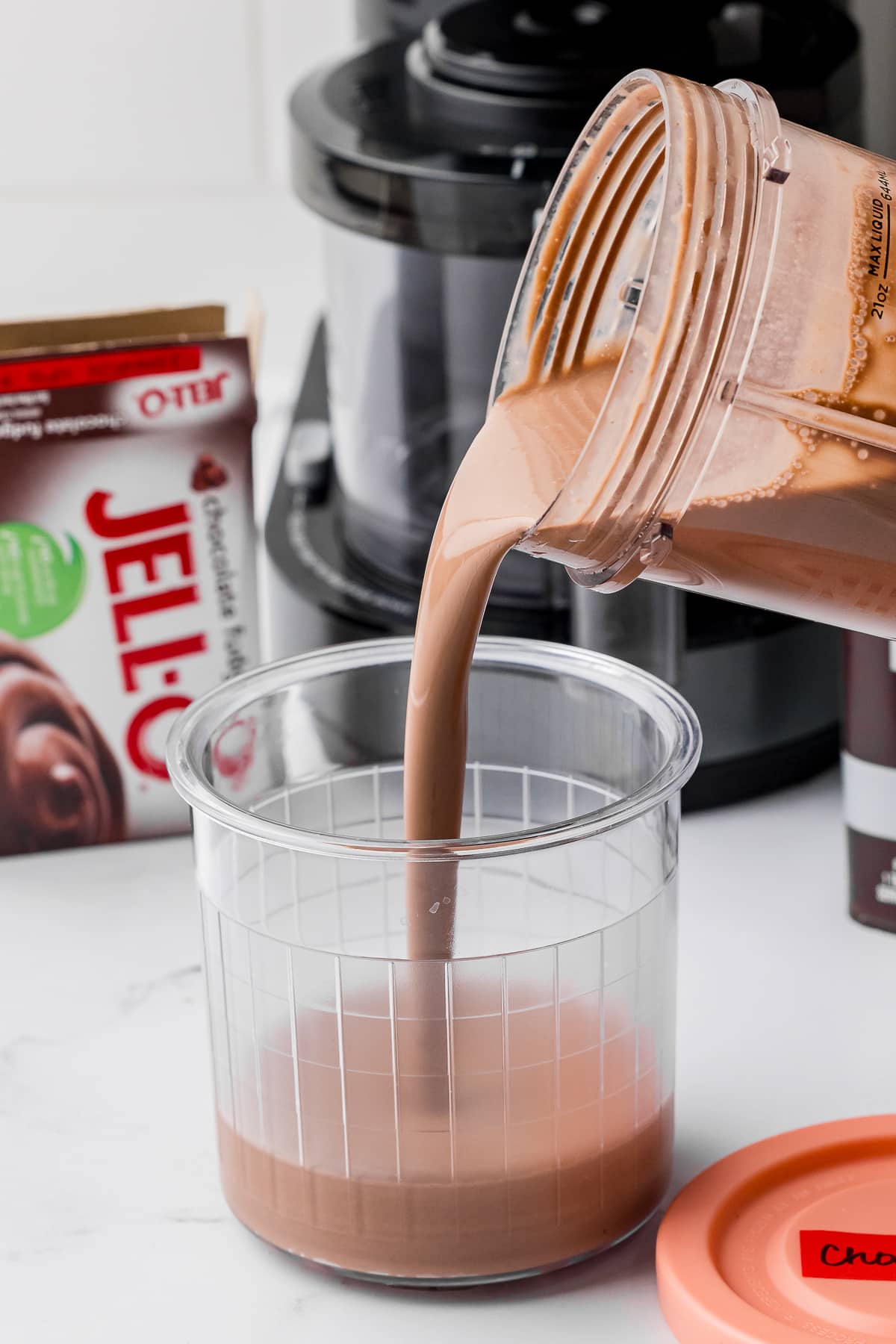 pouring the chocolate ice cream mixture into a ninja creami pint jar with jello box behind it