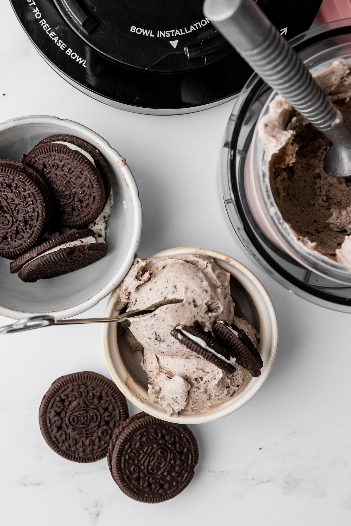 cookies and cream ice cream in a ramekin with oreos in a bowl and ice cream in the ninja creami pint with a heart spoon