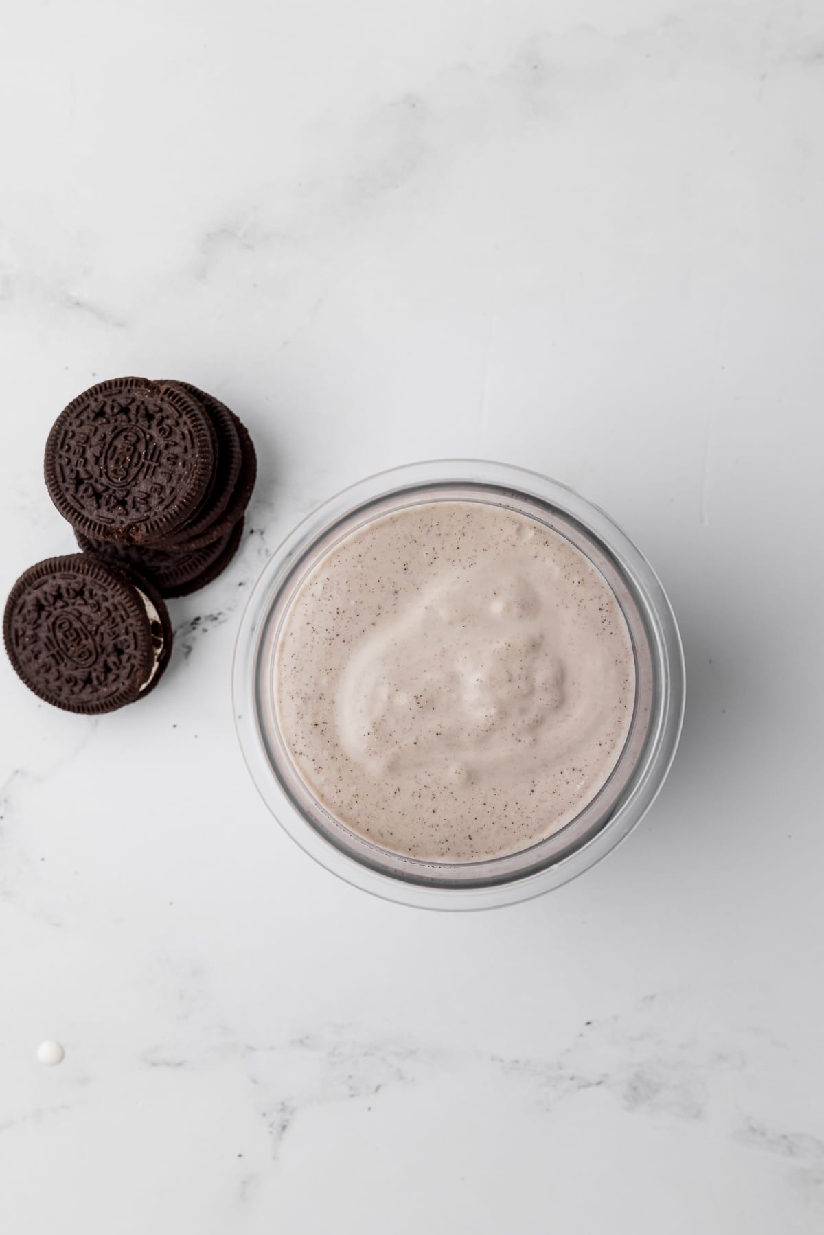 cookies and cream liquid in a pint jar with oreos on a white marble countertop