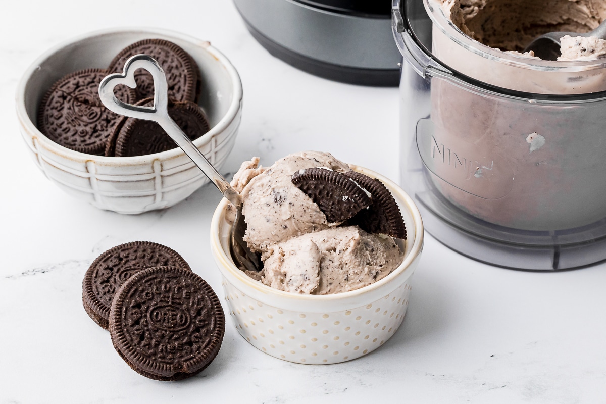 cookies and cream ice cream in a ramekin with oreos in a bowl and ice cream in the ninja creami pint outer container