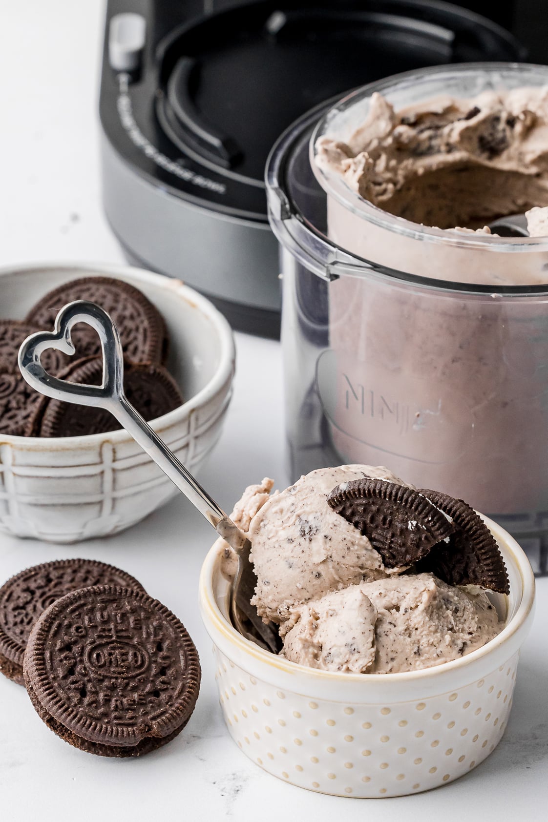 cookies and cream ice cream in a ramekin with oreos in a bowl and ice cream in the ninja creami pint