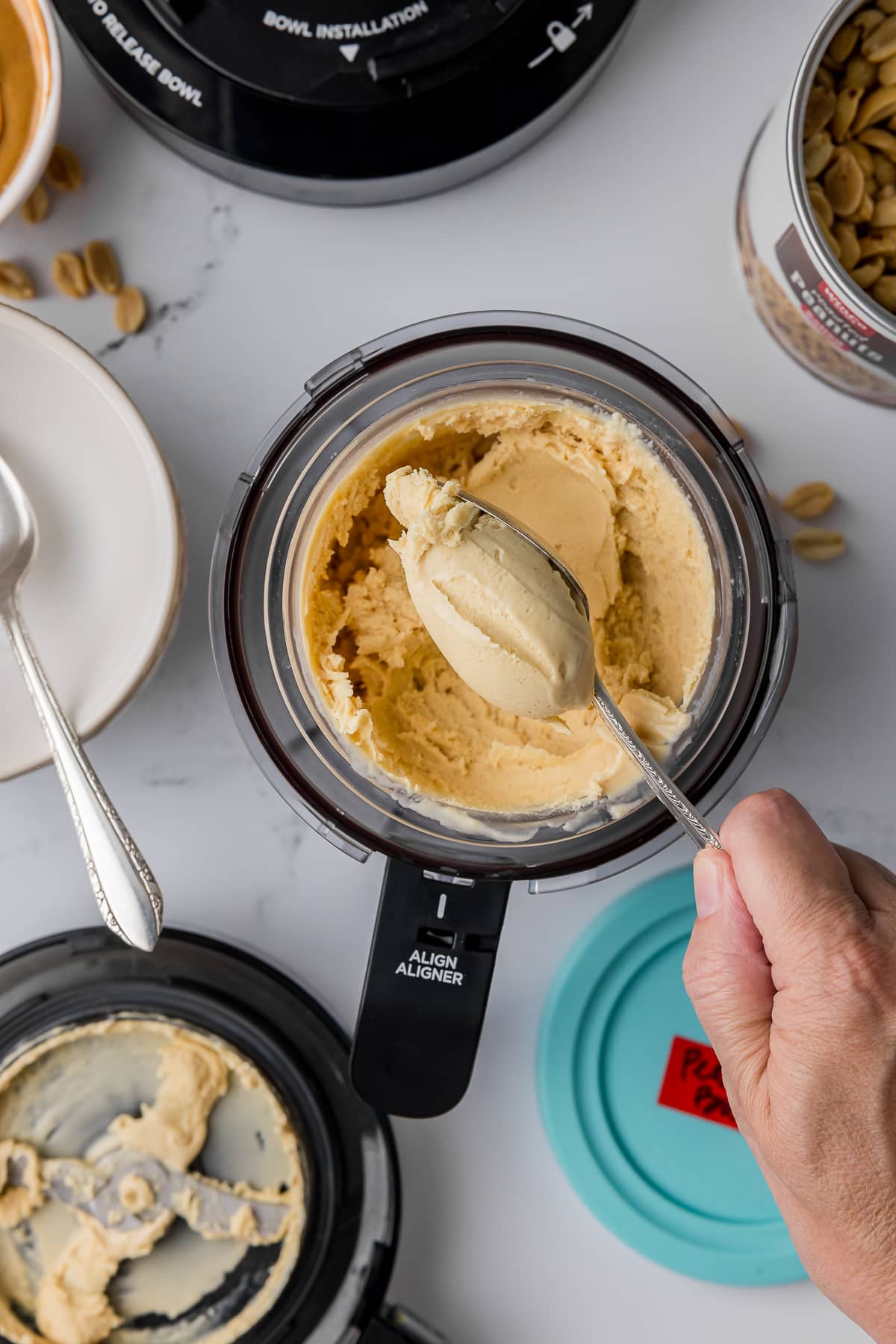 spoon full of peanut butter ice cream taken from a ninja creami pint jar that is sitting on a white countertop