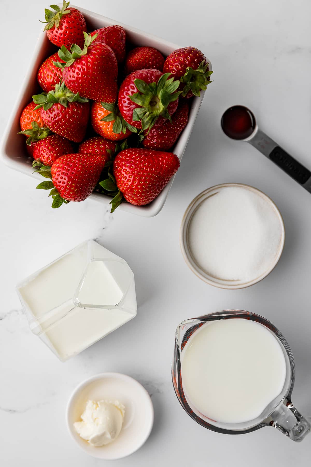 ingredients for strawberry ice cream including vanilla, fresh strawberries, sugar, cream cheese, milk, and cream