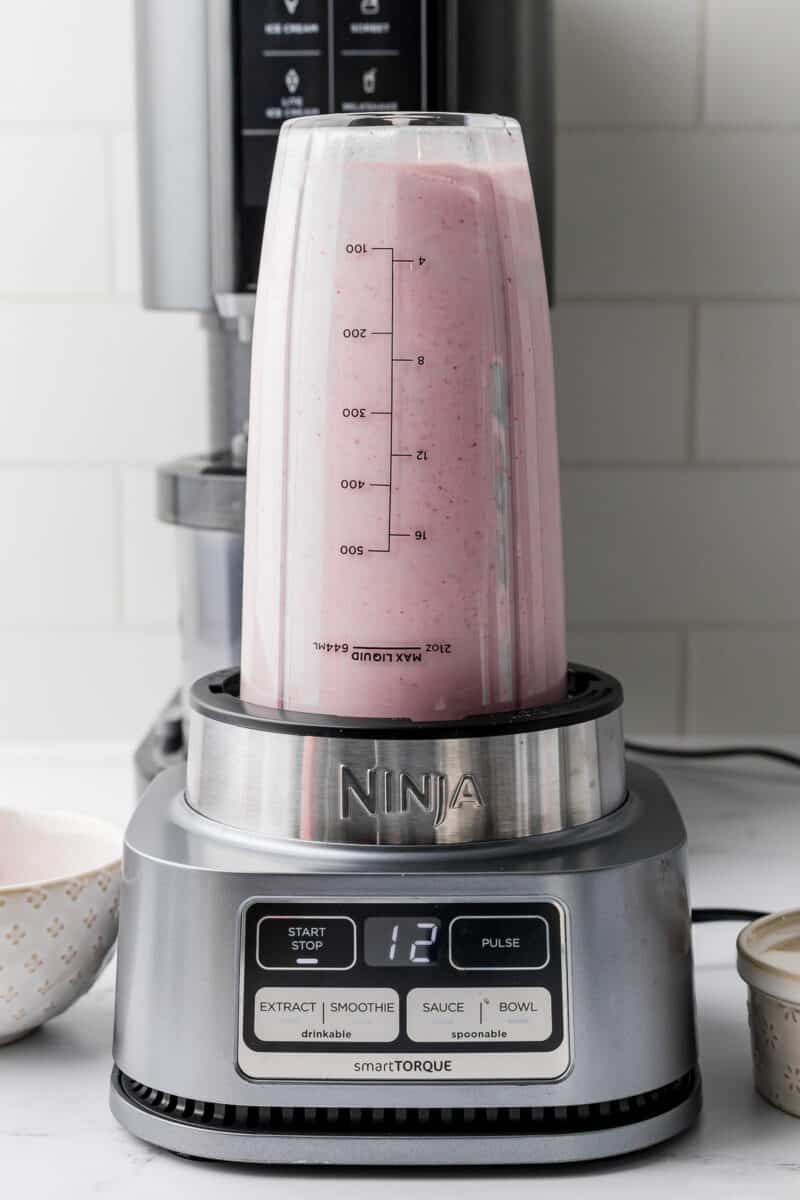 ninja smart torque blender with strawberry banana mixture on a white countertop