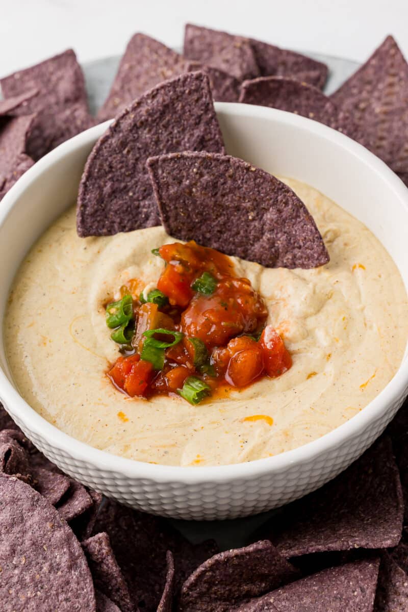 cottage cheese queso in a white bowl surrounded by blue corn tortilla chips