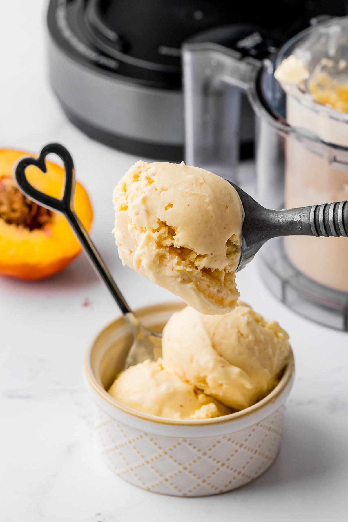 scoop on peach ice cream with a heart spoon and a ninja creami in the background