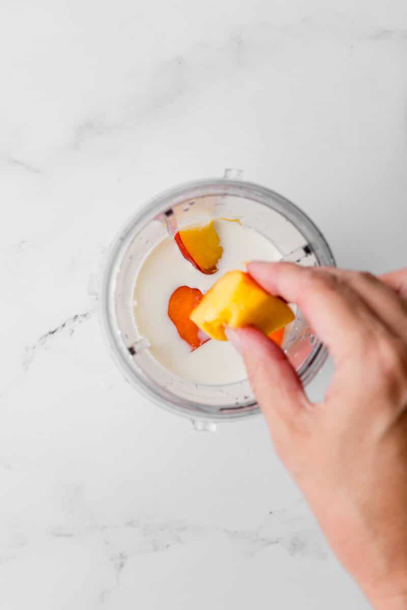 fresh peach pieces in a blender with milk and cream mixture