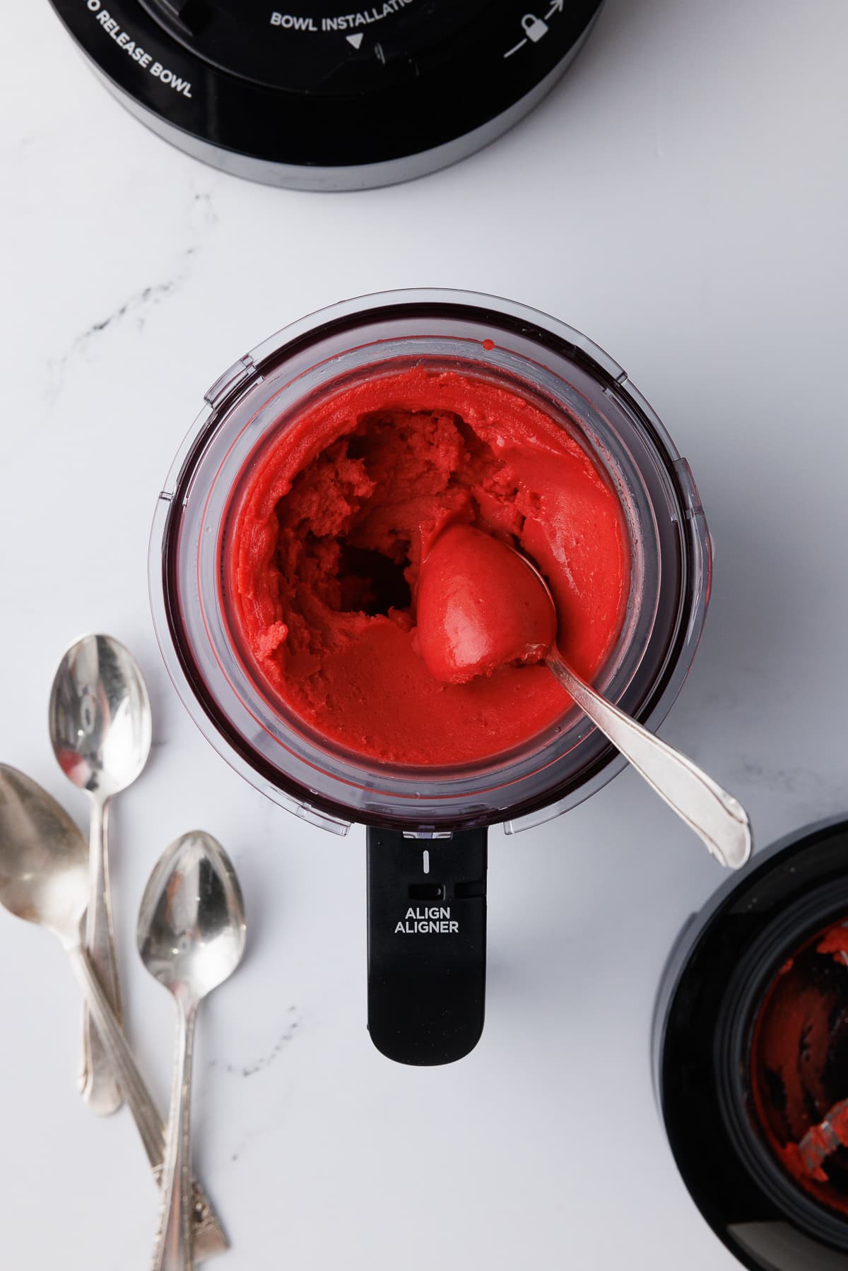 overhead shot of ice cream scoop in a ninja creami pint jar filled with strawberry sorbet