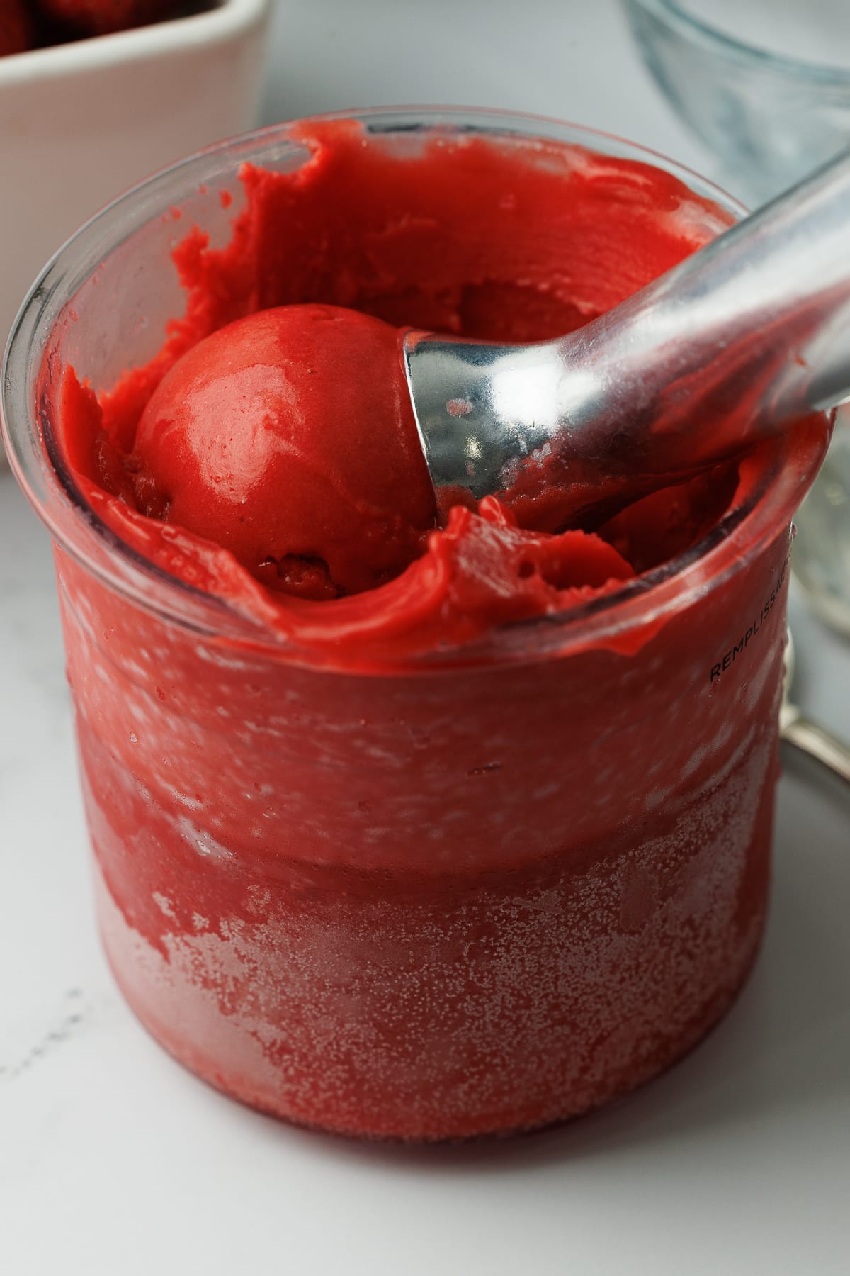 ice cream scoop in a ninja creami pint jar filled with strawberry sorbet